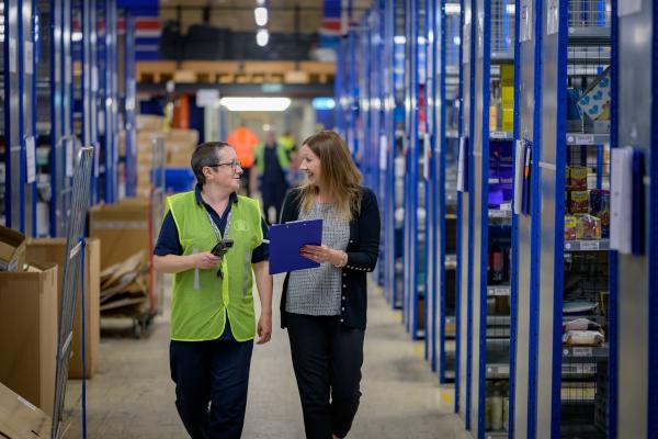 Image of two people walking together in a warehouse setting